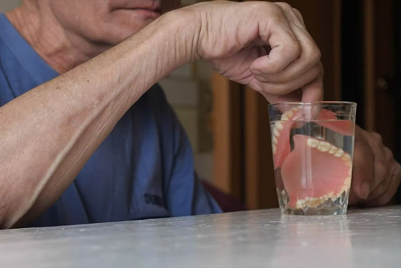 older man putting dentures away