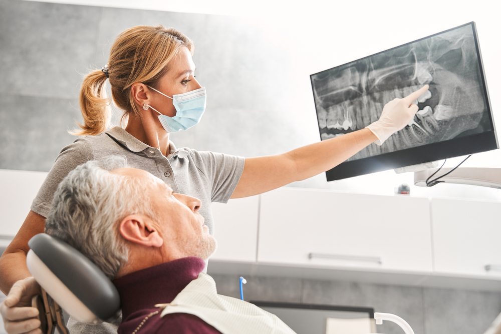 women dentist showing older man his xray